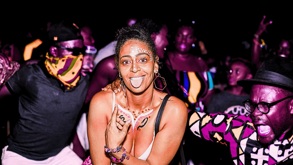 Woman at a party smiling and making a peace sign with her fingers, enjoying the festive atmosphere.