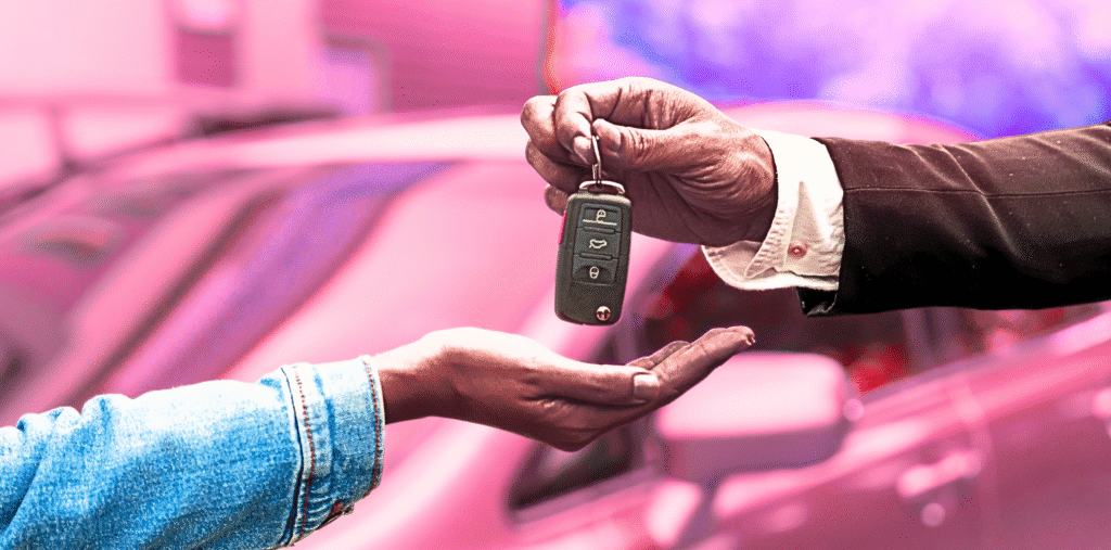Close-up of two hands exchanging a car key, symbolizing car rental or purchase.