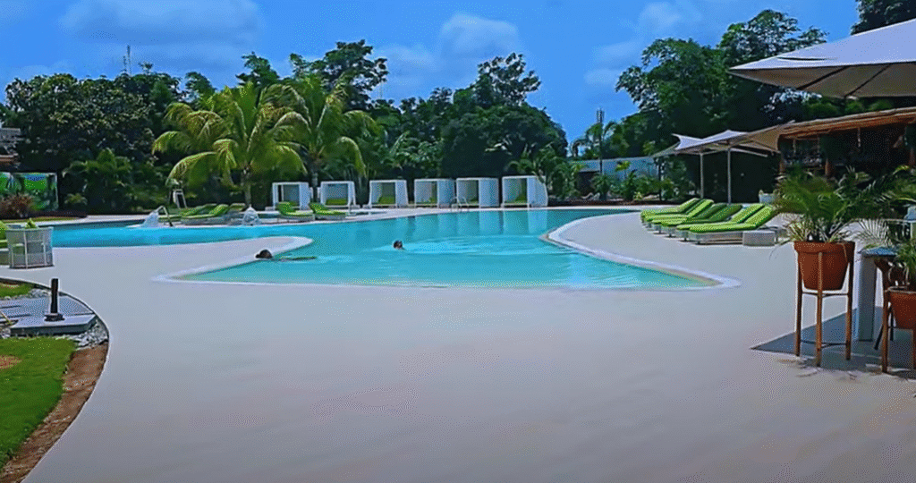 Elegant outdoor swimming pool at Kikuxi Club in Luanda, Angola, with palm trees, lounge beds, and a tropical, relaxed atmosphere.