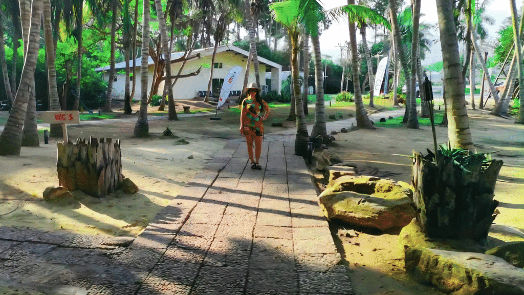 Woman walking through a resort pathway surrounded by palm trees and tropical greenery near Luanda.