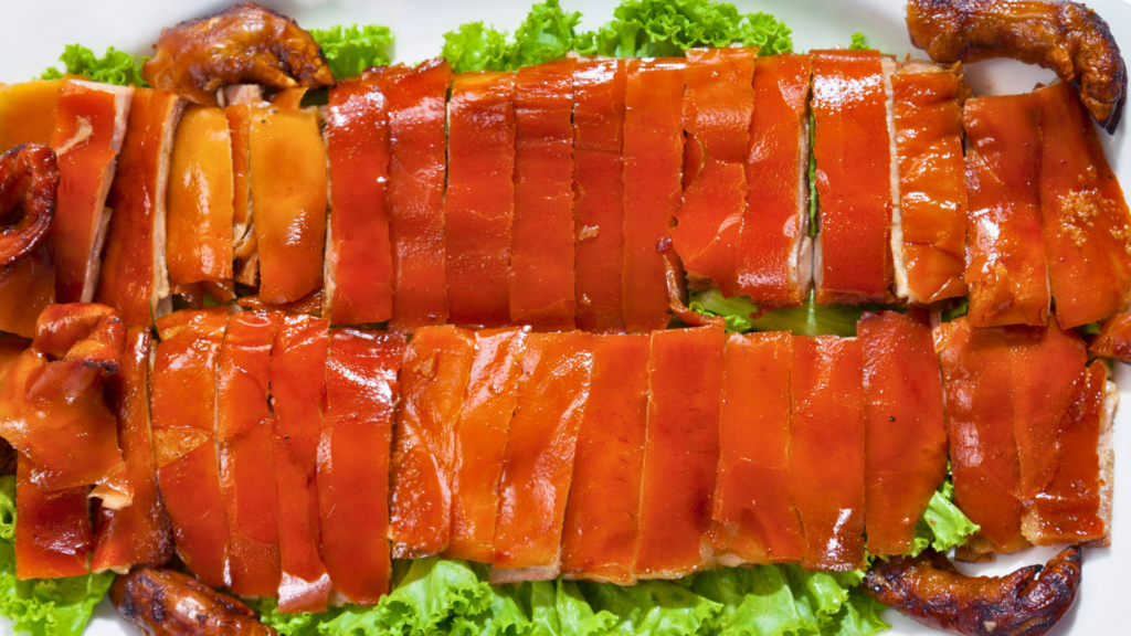 Traditional Portuguese roast suckling pig sliced into crispy pieces and served on a bed of fresh lettuce leaves.