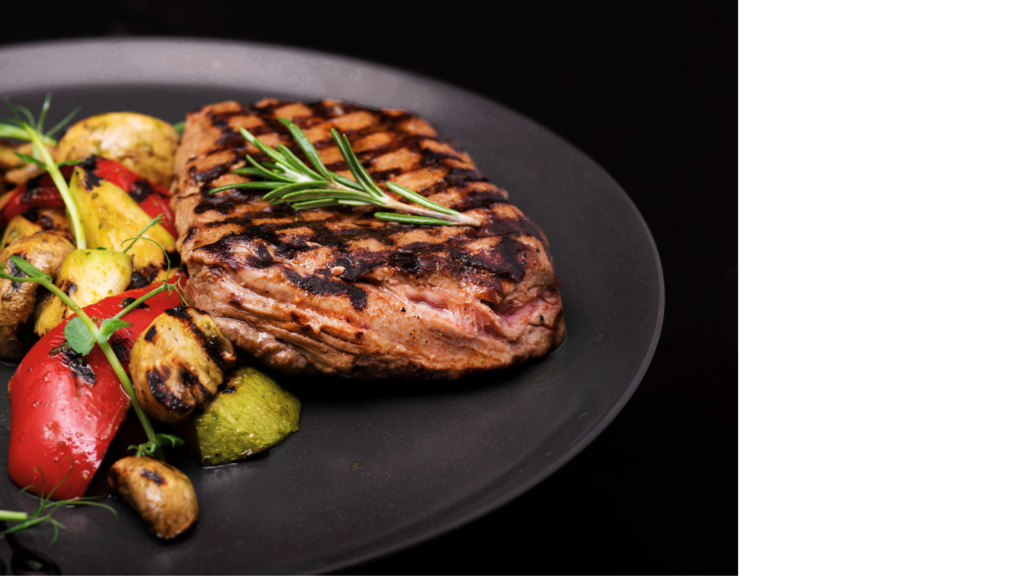 Perfectly grilled steak with charred zucchini, mushrooms, and red bell peppers, garnished with a sprig of rosemary.