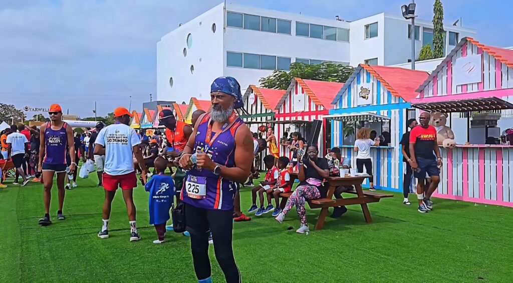 Colorful market stalls at the Talatona Fitness Fair 2025, with families, athletes and children enjoying the atmosphere after the race, surrounded by striped booths and a picnic area.