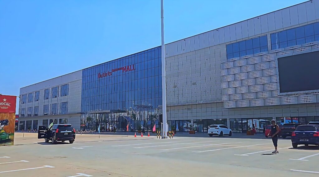 Front view of Outlets Shopping Angola in Zango, Luanda – a modern shopping mall with parking area and international brand stores.